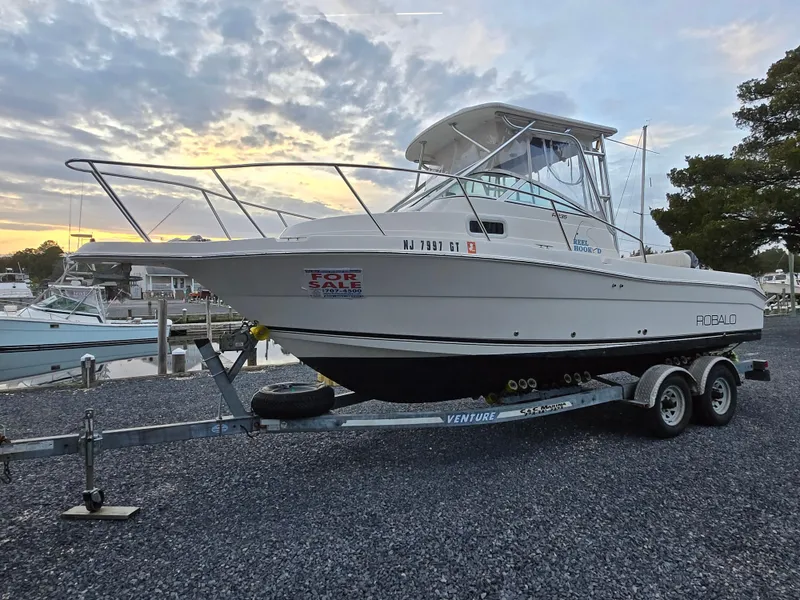 Slide: The Image of 2004 Robalo R235 Walkaround boat on trailer, for sale at marina during sunset. - 0