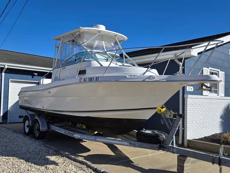 Slide: The Image of 2004 Robalo R235 Walkaround boat on trailer, parked beside a house. - 1