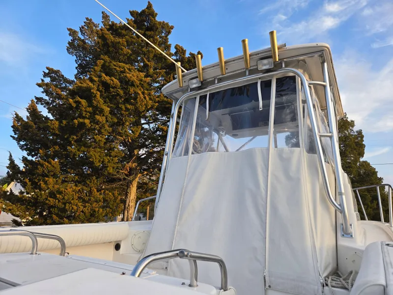 Slide: The Image of 2004 Robalo R235 Walkaround boat with canopy, surrounded by trees under a blue sky. - 11