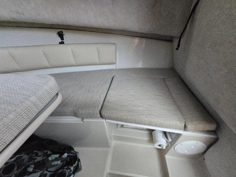 Slide: The Image of 2004 Robalo R235 Walkaround cabin interior with cushioned seating and storage space. - 22