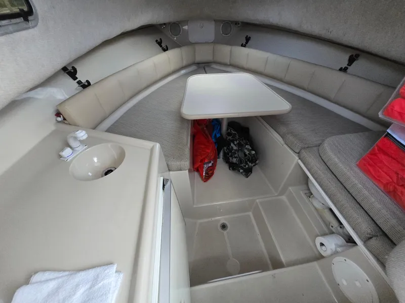 Slide: The Image of 2004 Robalo R235 Walkaround cabin interior with seating, table, and sink. - 25