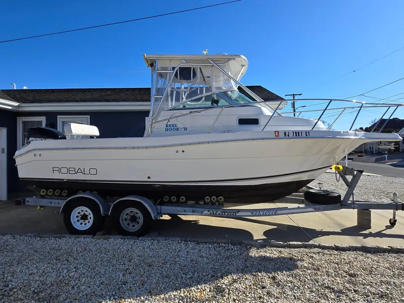 Slide: The Image of 2004 Robalo R235 Walkaround boat on trailer, parked outdoors, side view. - 3