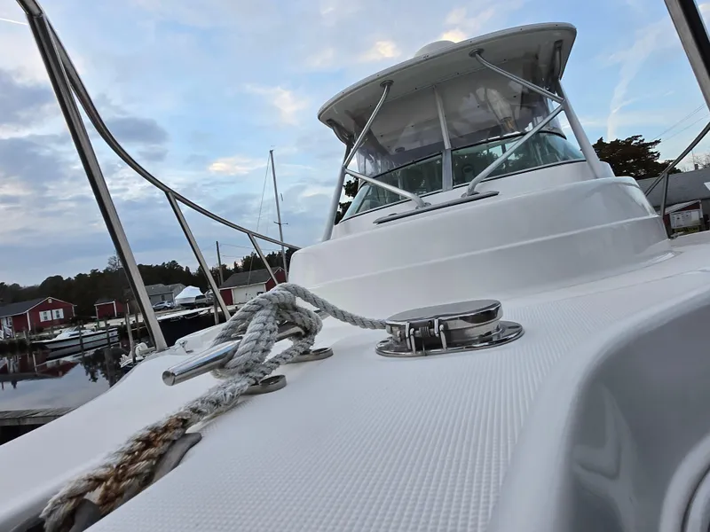 Slide: The Image of 2004 Robalo R235 Walkaround boat docked, showcasing deck and cabin under a cloudy sky. - 31