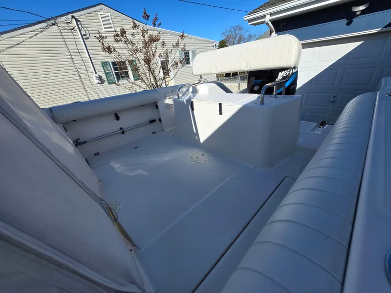 Slide: The Image of 2004 Robalo R235 Walkaround boat interior with seating and storage, parked near residential homes. - 4