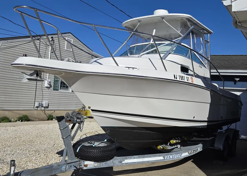 Slide: The Image of 2004 Robalo R235 Walkaround boat on trailer, parked near a house. - 7