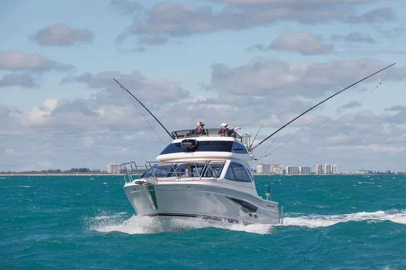 Slide: The Image of Solara S-310 SB 2026 boat cruising on ocean with fishing rods, city skyline in background. - 2