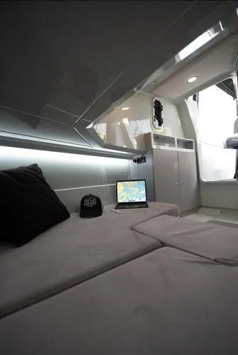 Slide: The Image of 2024 XO Boats DFNDR 9 interior with cozy seating, laptop, and cap. - 5