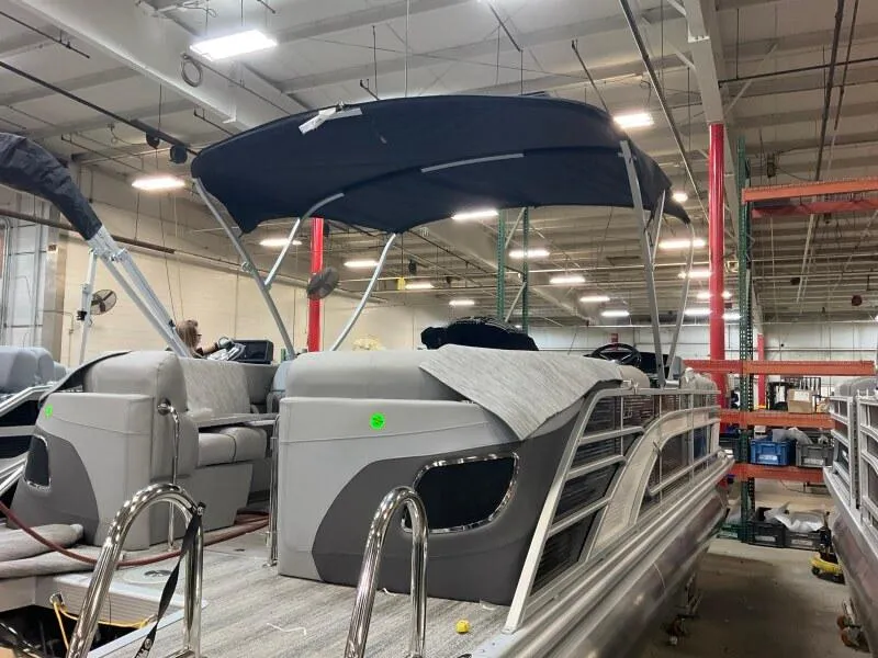 Slide: The Image of 2025 Bennington 23LFB pontoon boat in a warehouse, featuring a sleek design and canopy. - 5