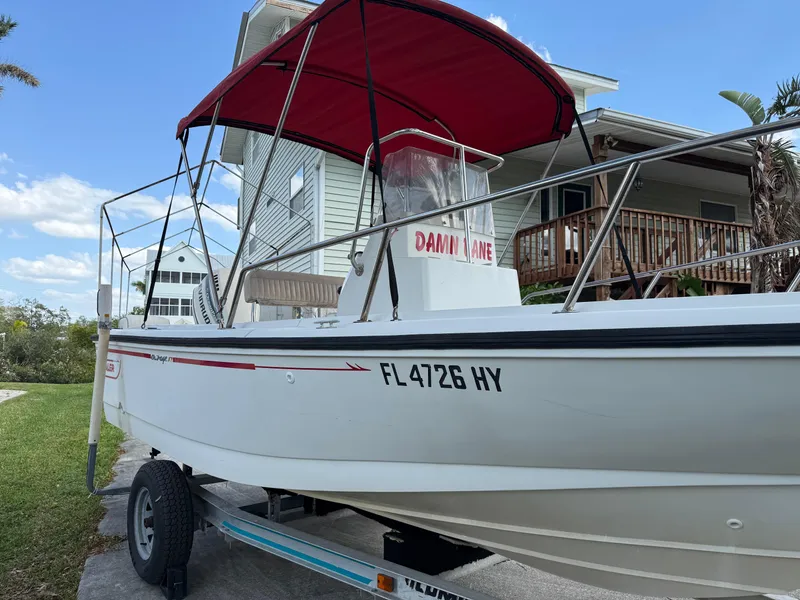 Slide: The Image of 1996 Boston Whaler Outrage 17 boat with red canopy on trailer, parked near house. - 1