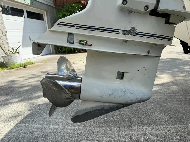 Slide: The Image of 1996 Boston Whaler Outrage 17 outboard motor with propeller, parked on concrete driveway. - 10