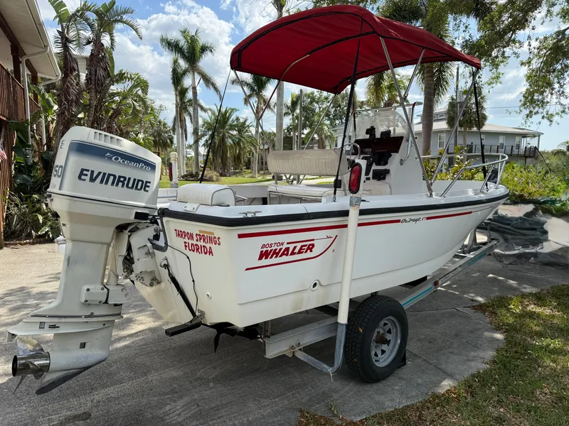 Slide: The Image of 1996 Boston Whaler Outrage 17 boat with Evinrude motor and red canopy in Florida setting. - 2