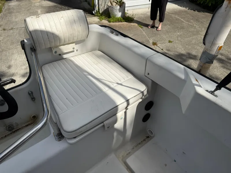 Slide: The Image of 1996 Boston Whaler Outrage 17 boat interior with white cushioned seating. - 20
