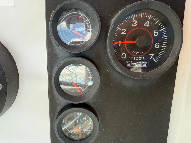 Slide: The Image of Instrument panel of a 1996 Boston Whaler Outrage 17 boat, featuring gauges and tachometer. - 37