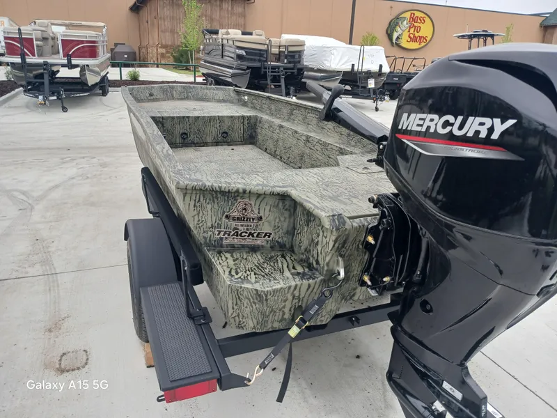 Slide: The Image of 2025 Tracker Grizzly 1650 T Prairie Wings Edition boat with Mercury engine in outdoor setting. - 2