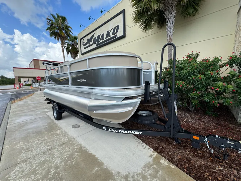 The Image of 2025 Sun Tracker Party Barge 18 DLX pontoon boat on trailer, parked outside dealership. - 0