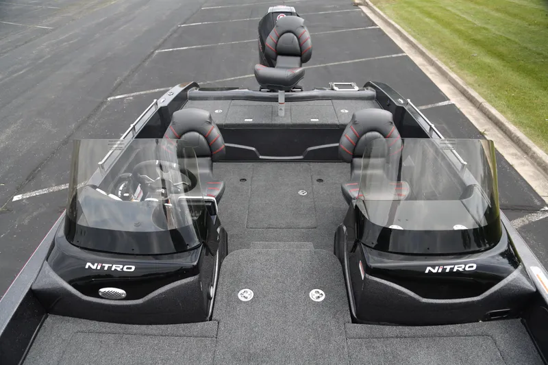 Slide: The Image of 2025 Nitro ZV19 boat interior with dual consoles and seating, parked on asphalt near grass. - 3
