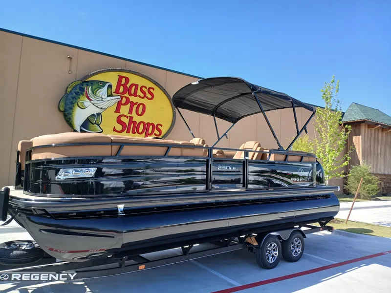 Slide: The Image of 2025 Regency 230 LE3 pontoon boat displayed at Bass Pro Shops. - 0