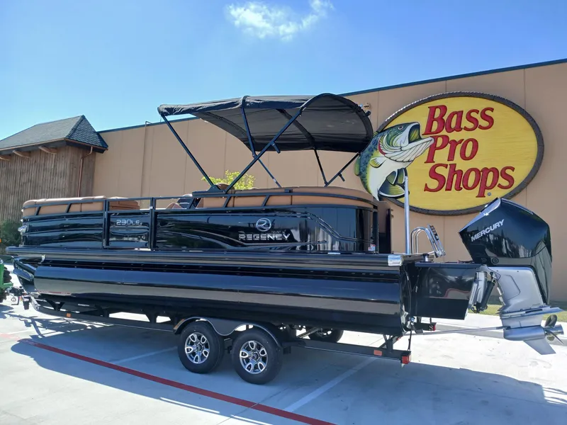 Slide: The Image of 2025 Regency 230 LE3 pontoon boat displayed outside Bass Pro Shops. - 1