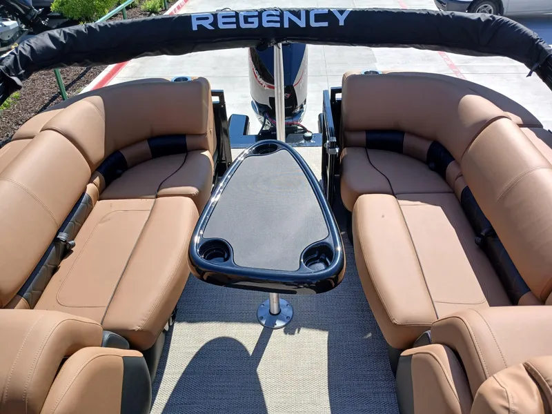 Slide: The Image of 2025 Regency 230 LE3 boat interior with tan seating and central table. - 9
