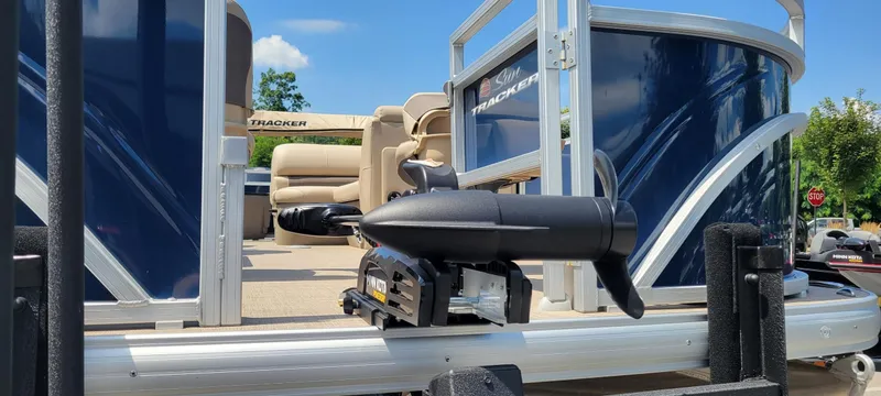 Slide: The Image of 2025 Sun Tracker Fishin' Barge 20 DLX pontoon boat with seating and motor, under clear blue sky. - 3