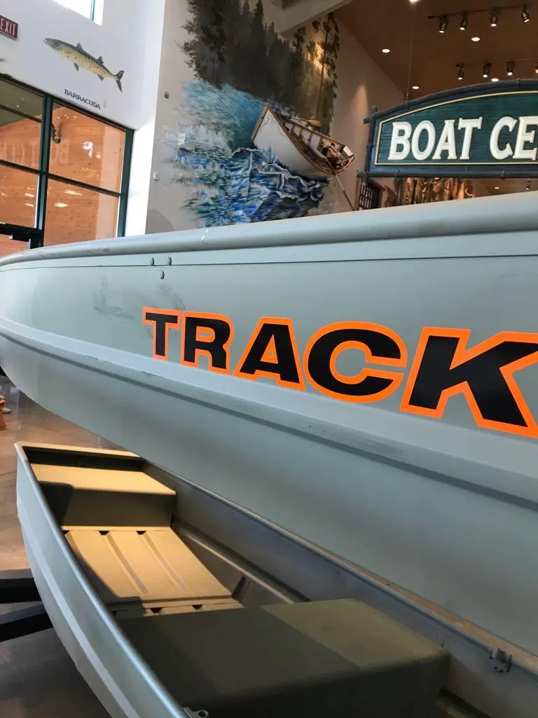 Slide: The Image of 2025 Tracker Grizzly 12 Jon boat displayed in a showroom with vibrant signage. - 4