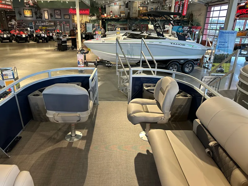 Slide: The Image of 2025 Sun Tracker Fishin' Barge 20 DLX interior with seating, displayed in a showroom. - 5
