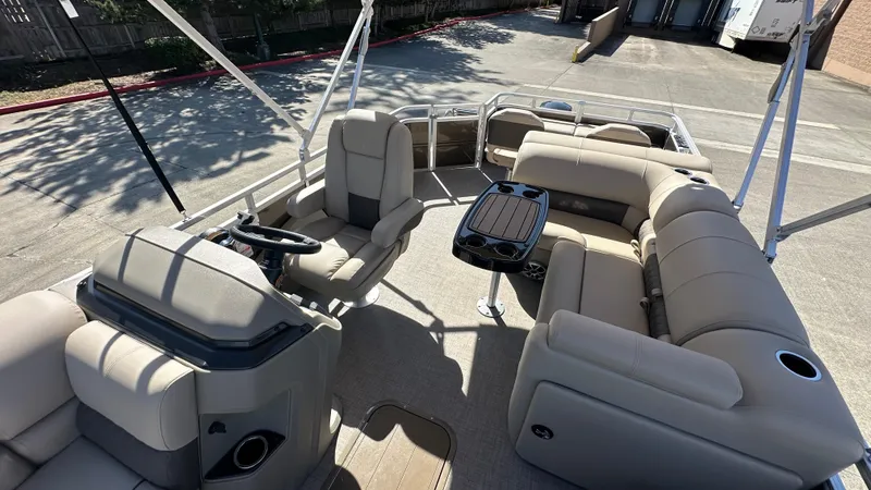 Slide: The Image of 2025 Sun Tracker SportFish 22 XP3 pontoon boat interior with beige seating and steering console. - 7
