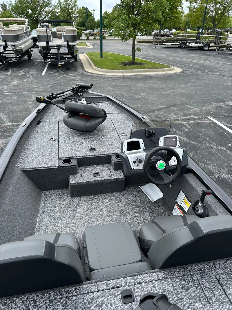 Slide: The Image of 2025 Tracker Pro Team 175 boat interior with steering console and seating in a parking lot. - 2