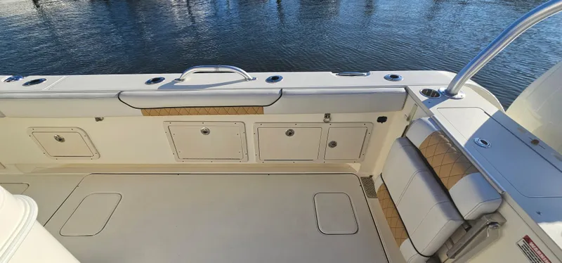 Slide: The Image of 2016 World Cat 320 boat deck with storage compartments and seating by the water. - 13
