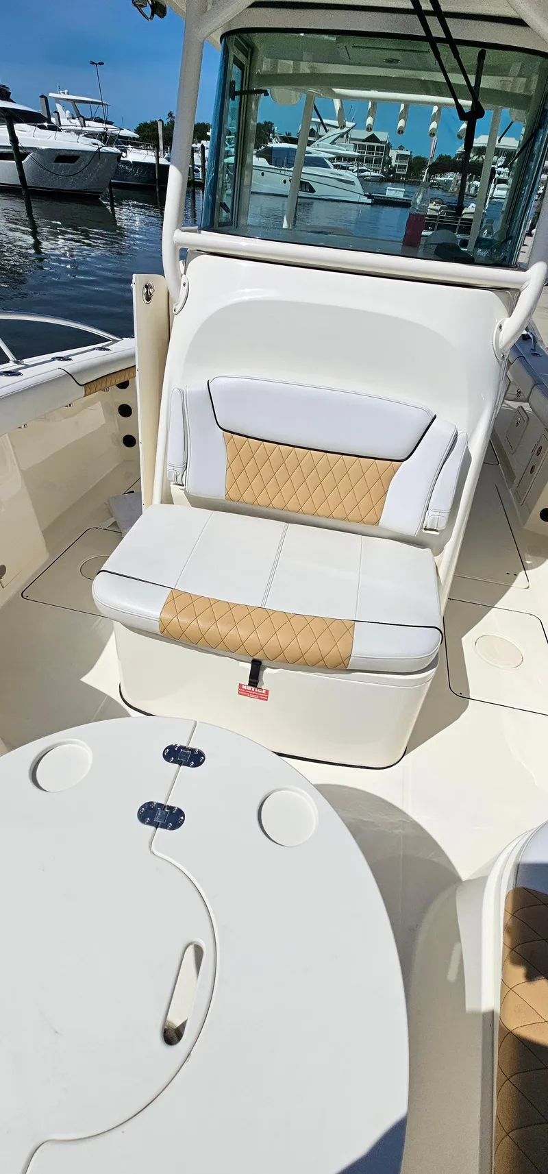 Slide: The Image of 2016 World Cat 320 boat interior with cushioned seating and table, docked at marina. - 25