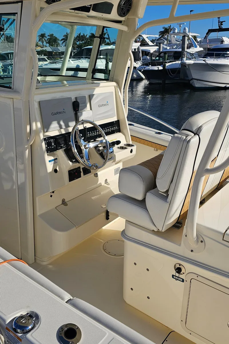Slide: The Image of 2016 World Cat 320 boat interior with steering wheel and seating, docked at marina. - 27