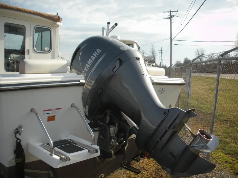 Slide: The Image of 2018 Parker 2120 Sport Cabin boat with Yamaha outboard motor, docked near a chain-link fence. - 17
