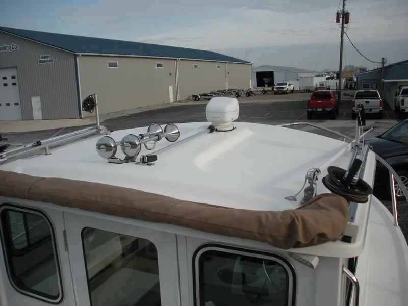 Slide: The Image of 2018 Parker 2120 Sport Cabin boat roof with radar and lights in a marina setting. - 3