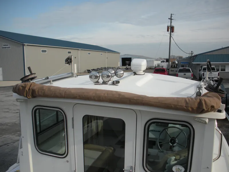 Slide: The Image of 2018 Parker 2120 Sport Cabin boat with rooftop equipment, parked near industrial buildings. - 4