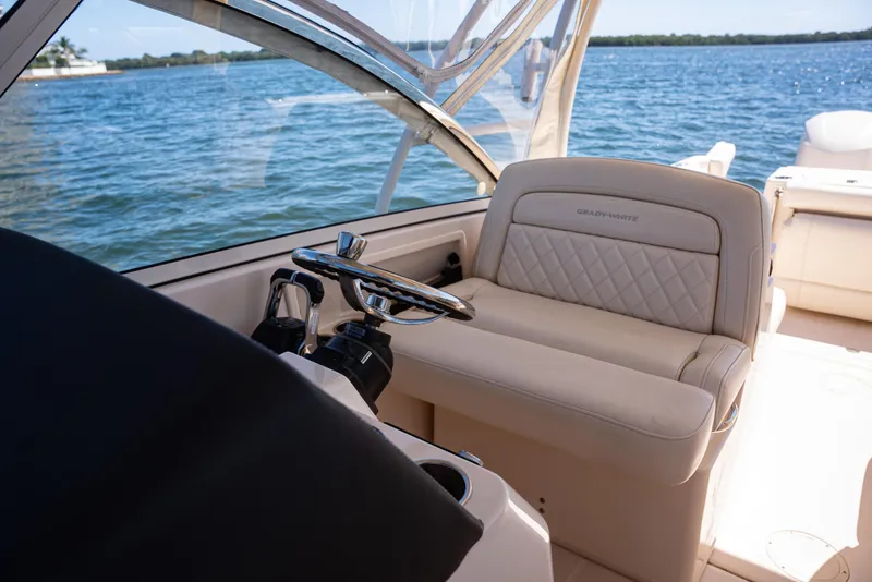 Slide: The Image of 2020 Grady-White Freedom 285 boat interior with steering wheel and seating, on calm water. - 26