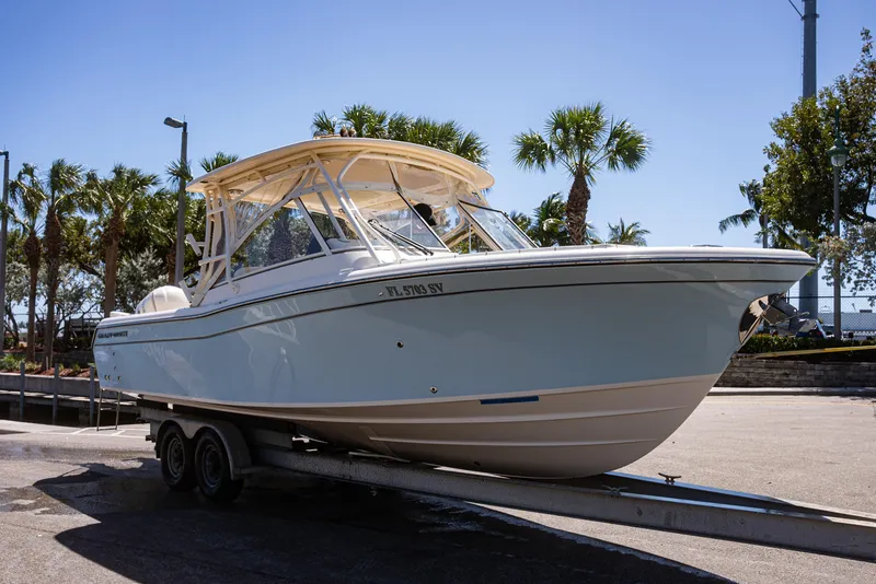 Slide: The Image of 2020 Grady-White Freedom 285 boat on trailer, parked near palm trees. - 33