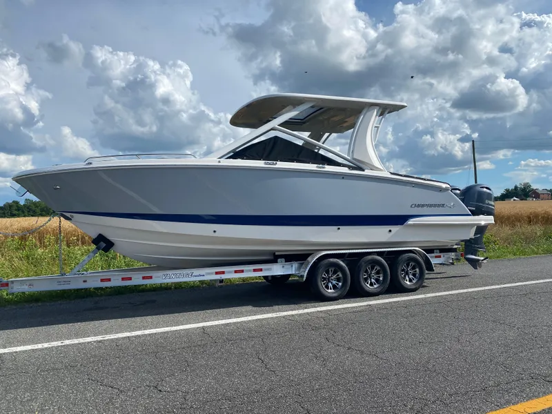 Slide: The Image of 2025 Chaparral 280 OSX boat on trailer, parked on roadside under cloudy sky. - 0
