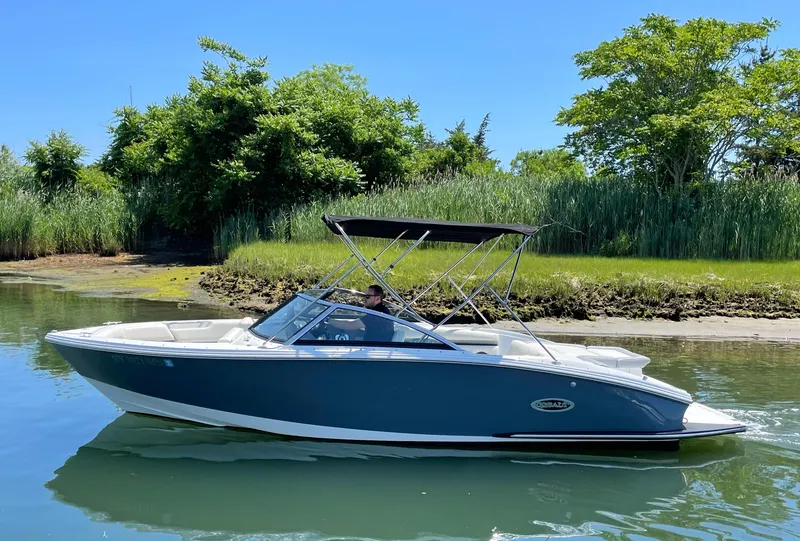 Slide: The Image of 2018 Cobalt CS22 boat cruising on a calm river with lush greenery. - 0