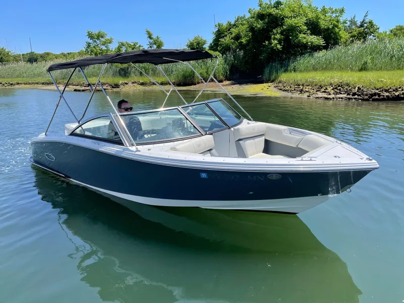 Slide: The Image of 2018 Cobalt CS22 boat cruising on a calm lake with lush greenery. - 1
