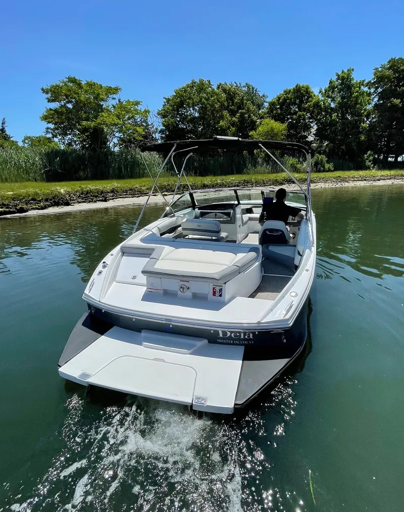 Slide: The Image of 2018 Cobalt CS22 boat cruising on a calm lake near a lush shoreline. - 3
