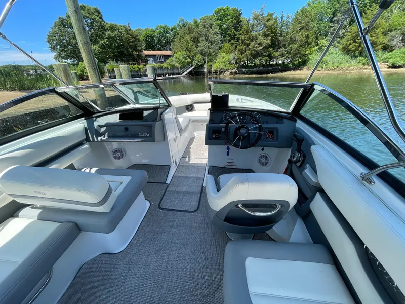 Slide: The Image of 2018 Cobalt CS22 boat interior with seating and steering, docked by a scenic waterfront. - 4