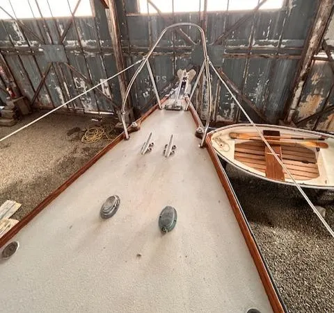 Slide: The Image of 1972 Bristol 40 sailboat deck in rustic boathouse, with small wooden dinghy nearby. - 13