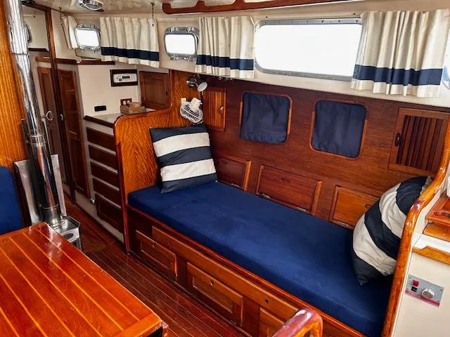 Slide: The Image of Interior of a 1972 Bristol 40 sailboat with wooden furnishings and blue cushions. - 17