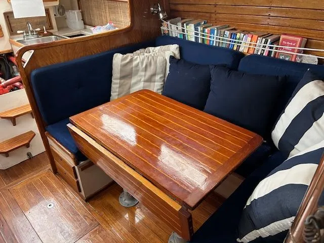 Slide: The Image of 1972 Bristol 40 yacht interior with wooden table, blue cushions, and bookshelf. - 20