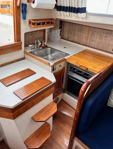Slide: The Image of 1972 Bristol 40 yacht interior with compact kitchen, wooden accents, and cozy seating area. - 23