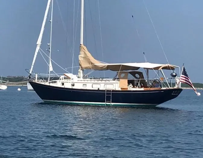 Slide: The Image of 1972 Bristol 40 sailboat anchored on calm water with American flag. - 5