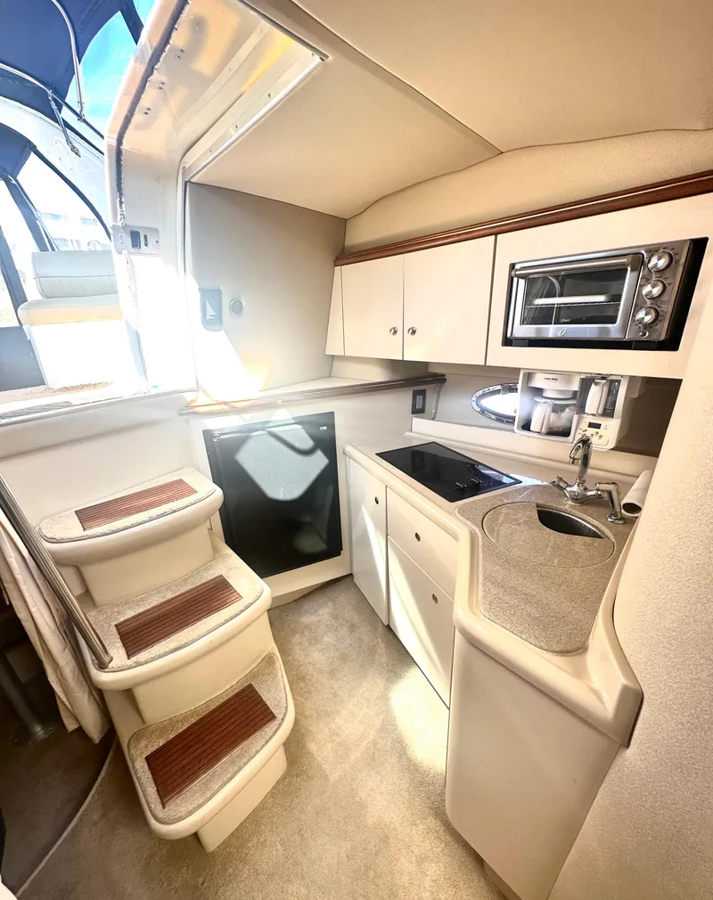 Slide: The Image of 2003 Cruisers Yachts 3372 Express interior kitchen with stairs, sink, and microwave. - 6