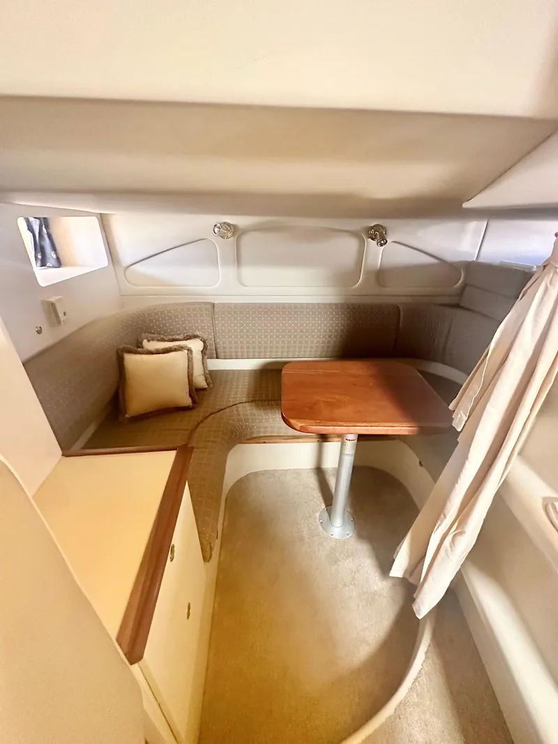 Slide: The Image of Interior of 2003 Cruisers Yachts 3372 Express, featuring cozy seating and a wooden table. - 8