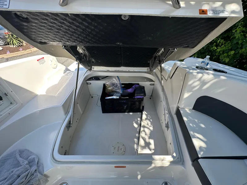 Slide: The Image of 2023 Chaparral 270 OSX boat storage compartment with open hatch and stored items. - 16