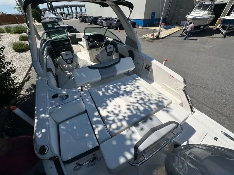 Slide: The Image of 2023 Chaparral 270 OSX boat with spacious seating and modern design in a marina setting. - 18